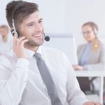 Smiling customer service representative using headset and computer at work