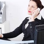 Pretty caucasian businesswoman answering the phone in the office.