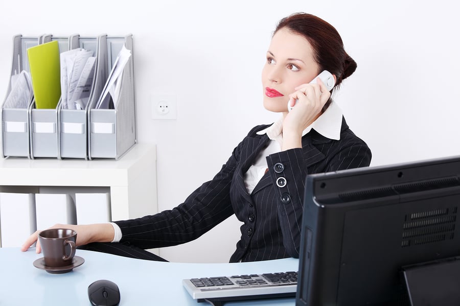 Pretty caucasian businesswoman answering the phone in the office.