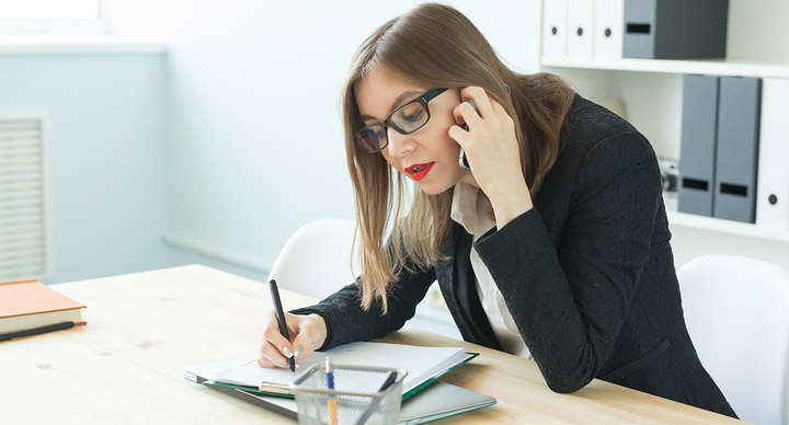 Young woman talking on the phone and making notes