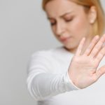 Close up of angry woman refuses offer, showing a gesture of refusing junk food, rejects something unpleasant, selective focus. Negative emotion, hand gestures.