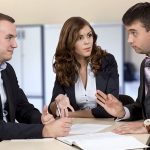 Business negotiations Group of three business people, male and female, discussing the deal. Office interior, serious, authentic emotions